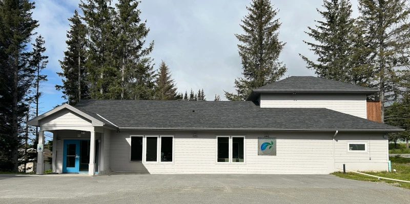 White building with a grey roof and blue doors.
